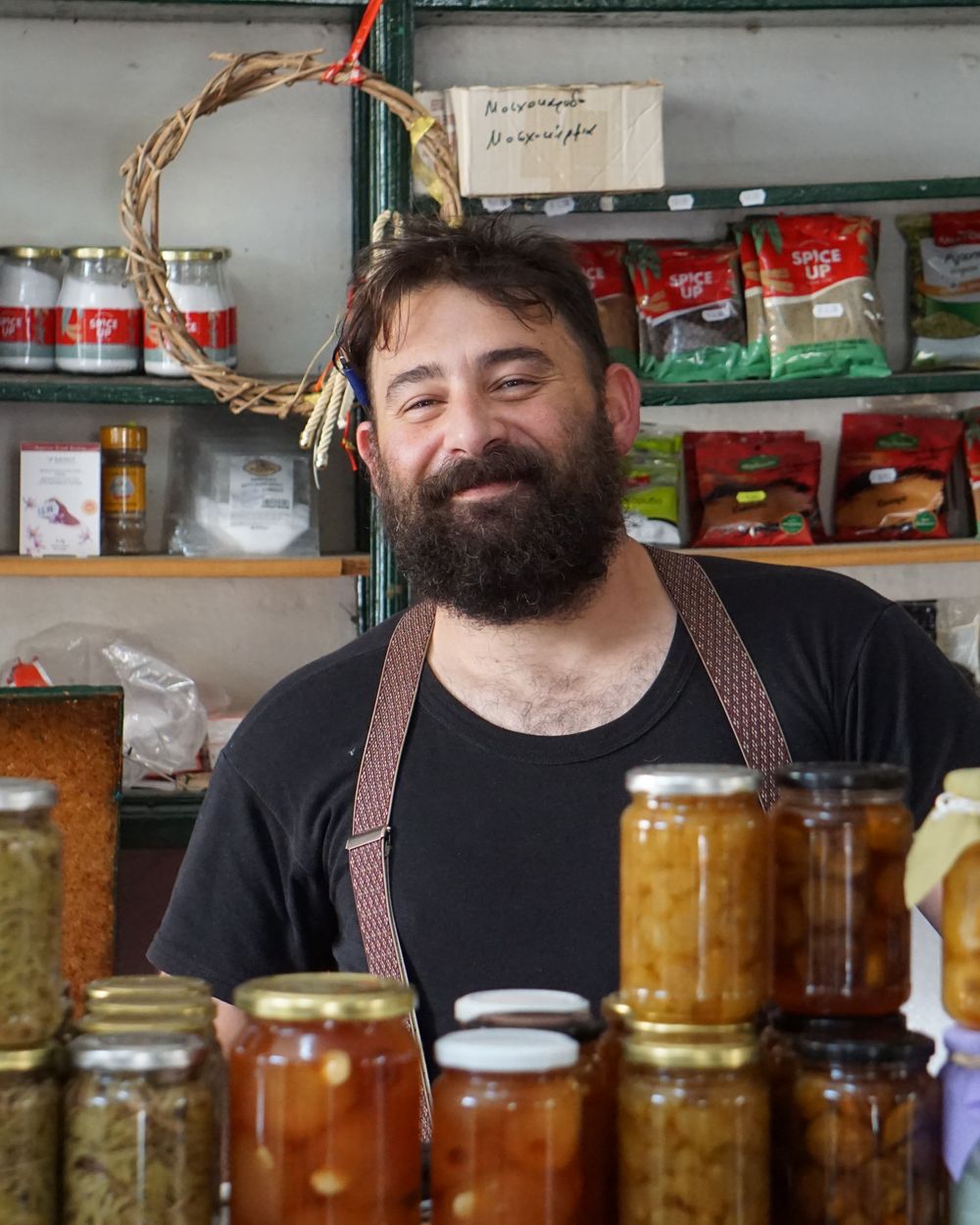 Comerciante sonriendo en su negocio, rodeado de sus productos